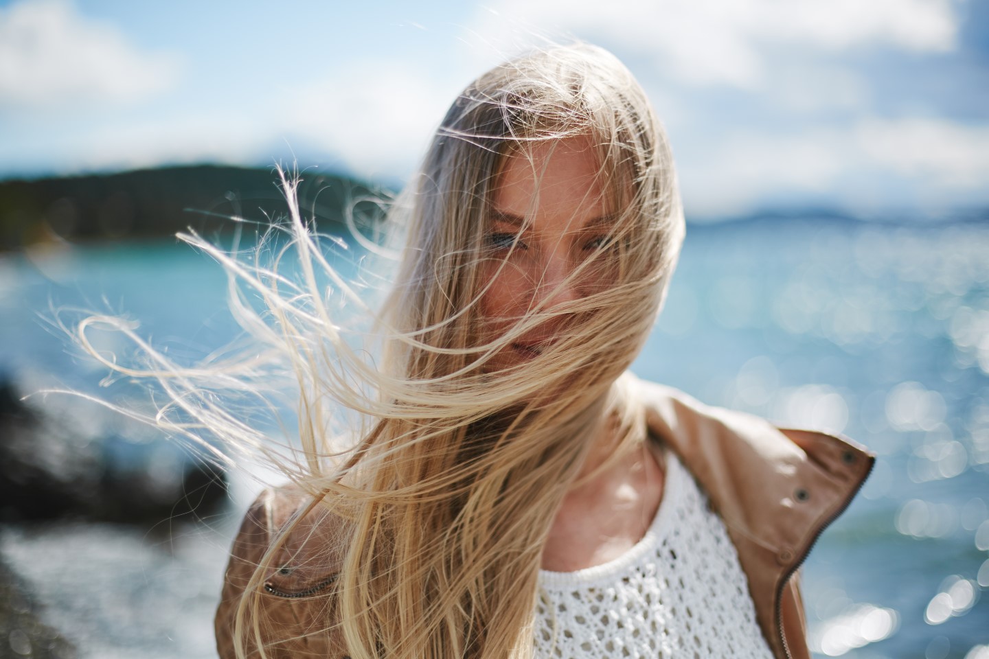 blond girl with long hair looking at camera by the seaside